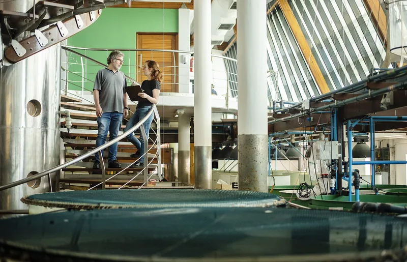 Vernon Coyne and Sarah Carroll standing in an indoor aquaculture facility