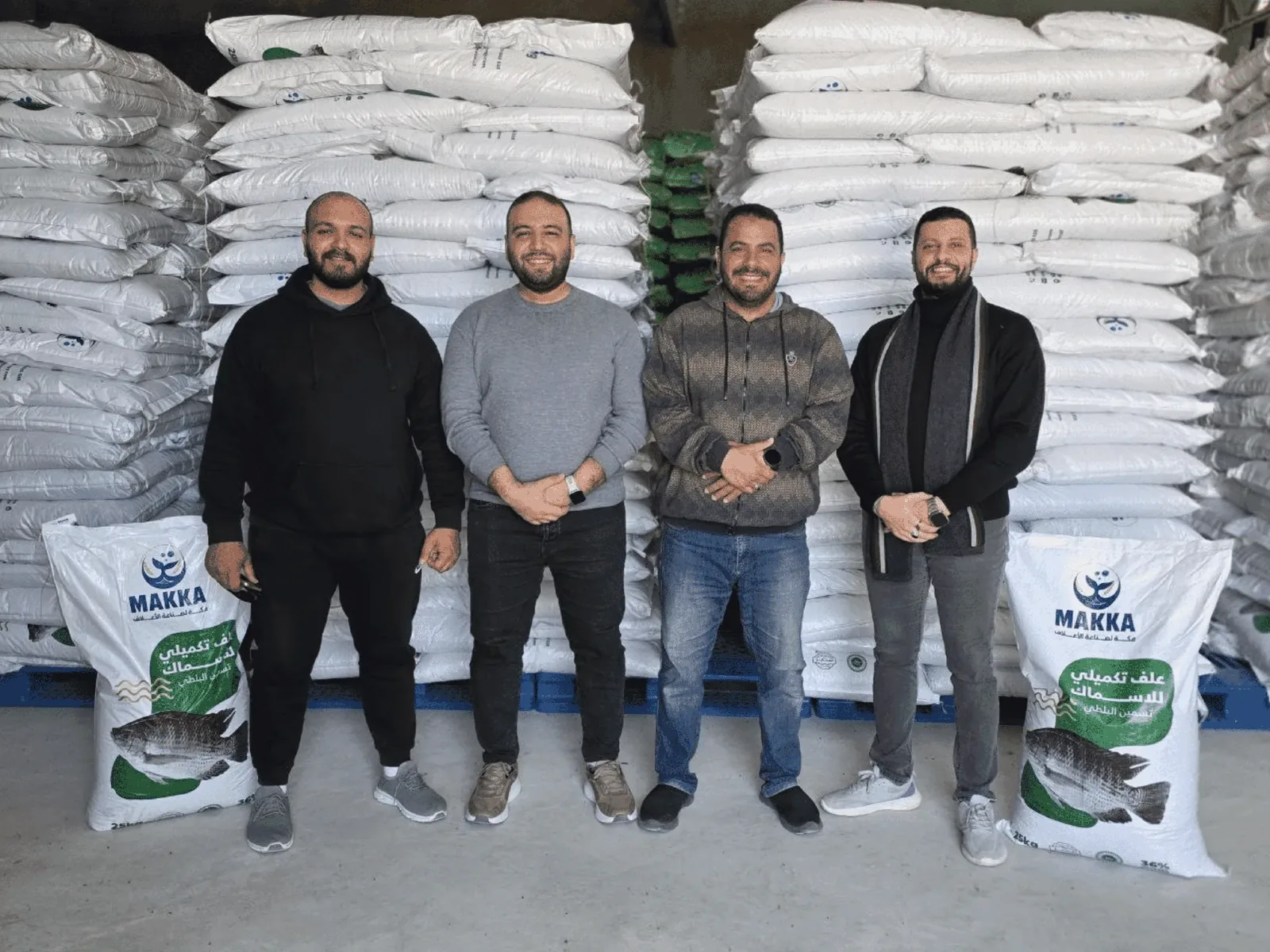 A group of four people standing infront of aquafeed bags.